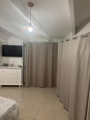 a bedroom with curtains and a bed and a tv at Bas de villa Sarrola Carcopino in Sarrola-Carcopino