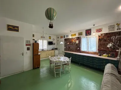 a room with a table and a kitchen with green floors at Bas de villa Sarrola Carcopino in Sarrola-Carcopino