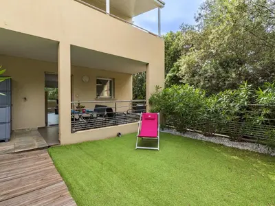 a pink chair sitting on the grass in a yard at Apartment Clos Vignola by Interhome in Porto-Vecchio