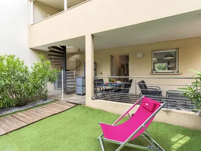 a pink chair sitting on a lawn in front of a house at Apartment Clos Vignola by Interhome in Porto-Vecchio
