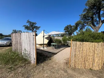a wooden fence with a table and an umbrella at Le Tipi in Lecci