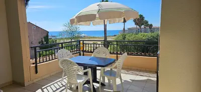 a table and chairs on a balcony with an umbrella at Palmeraie 131-Clim-PISCINE EN RESIDENCE in Sari Solenzara