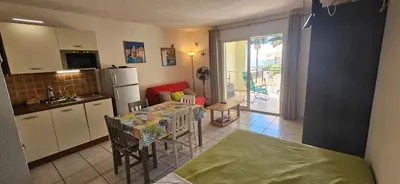 a kitchen with a table and a kitchen with a refrigerator at Palmeraie 131-Clim-PISCINE EN RESIDENCE in Sari Solenzara