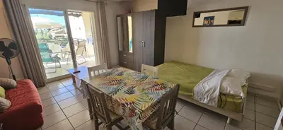 a room with a bed and a table and a window at Palmeraie 131-Clim-PISCINE EN RESIDENCE in Sari Solenzara