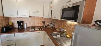 a kitchen with white cabinets and a sink and a microwave at Palmeraie 131-Clim-PISCINE EN RESIDENCE in Sari Solenzara