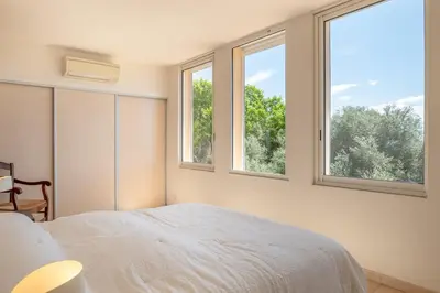 a bedroom with a bed and two windows at Family Villa with Pool and Sublime Sea View in Olmeto