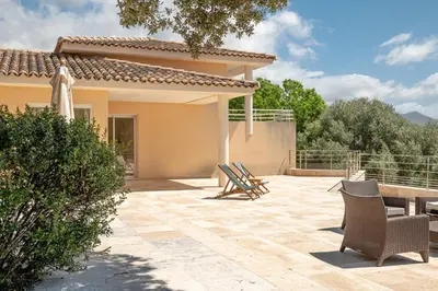 a patio with chairs and a house at Family Villa with Pool and Sublime Sea View in Olmeto