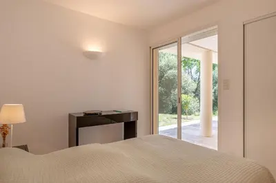 a bedroom with a bed and a sliding glass door at Family Villa with Pool and Sublime Sea View in Olmeto