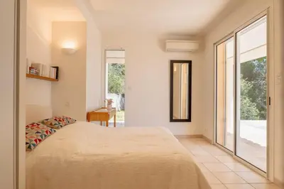 a bedroom with a bed and a large window at Family Villa with Pool and Sublime Sea View in Olmeto