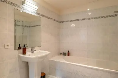 a white bathroom with a sink and a bath tub at Family Villa with Pool and Sublime Sea View in Olmeto