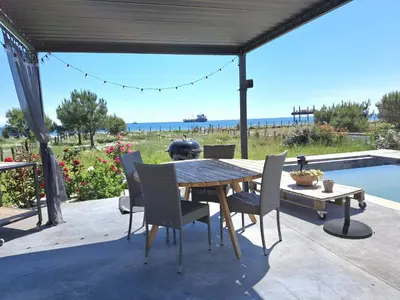 a patio with a table and chairs and a pool at Villa bord de mer avec piscine in Lucciana