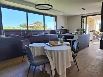a dining room with two tables and a kitchen at Villa bord de mer avec piscine in Lucciana