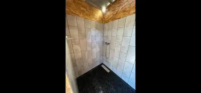 a bathroom with a shower with a tiled wall at Le Tipi 2 in Lecci