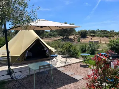 a tent with chairs and a table and an umbrella at Le Tipi 2 in Lecci