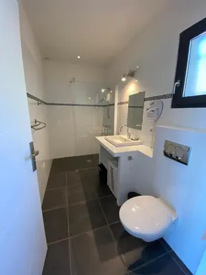 a white bathroom with a toilet and a sink at La résidence Location Pinarello in Mangialla