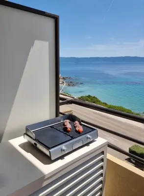 a grill on a table with a view of the ocean at Beau Studio vue sur mer, route des sanguinaires in Ajaccio