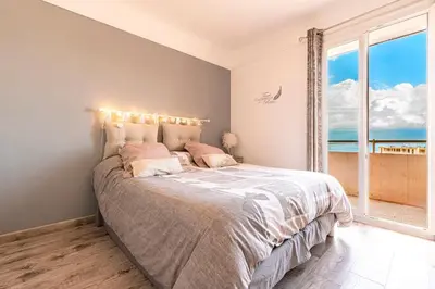 a bedroom with a bed with a view of the ocean at Le Renoso - Climatisé vue mer et montagne in Ajaccio