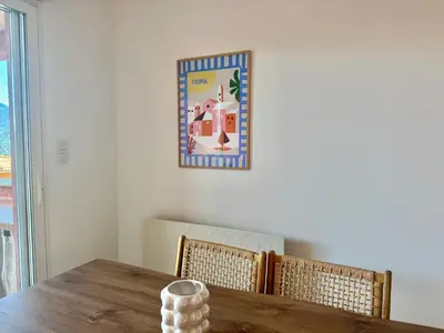 a dining room table with two chairs and a picture on the wall at Deux pièces tout confort sur les hauteurs de Propriano in Propriano