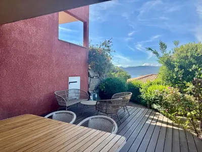a patio with a table and chairs on a wooden deck at Deux pièces tout confort sur les hauteurs de Propriano in Propriano