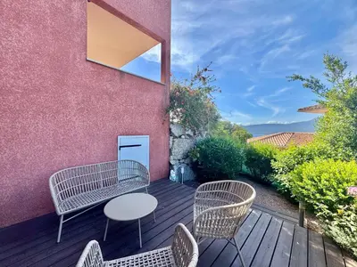 a patio with chairs and a table on a wooden deck at Deux pièces tout confort sur les hauteurs de Propriano in Propriano