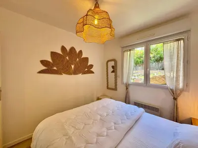 a bedroom with a large bed and a chandelier at Deux pièces tout confort sur les hauteurs de Propriano in Propriano