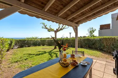 a table with a bowl of fruit on it under a pergola at Prunete - Piscine - Vue mer in Cervione