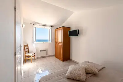 a bedroom with a bed and a window and a chair at Prunete - Piscine - Vue mer in Cervione