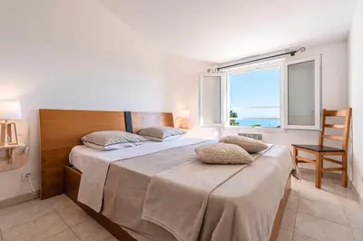a bedroom with a bed with a chair and a window at Prunete - Piscine - Vue mer in Cervione