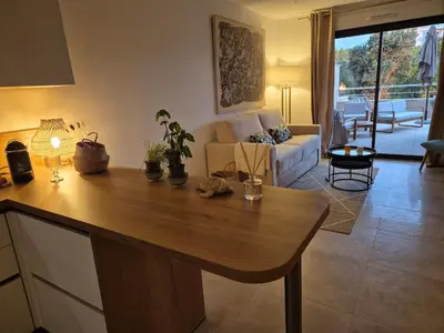 a kitchen and living room with a table and a couch at Appartement Neuf Grande Terrasse AGOSTA PLAGE in Albitreccia