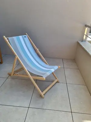 a beach chair sitting on a tiled floor at Appartement Neuf Grande Terrasse AGOSTA PLAGE in Albitreccia