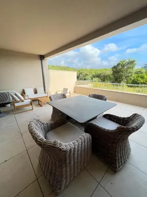 a patio with a table and chairs on a balcony at Appartement Neuf Grande Terrasse AGOSTA PLAGE in Albitreccia