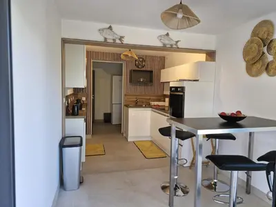 a kitchen with a table and a dining room at Maison Rez-de-jardin 80 m de la plage in Serra-di-Ferro