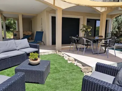 a patio with a couch and a table and chairs at Maison Rez-de-jardin 80 m de la plage in Serra-di-Ferro