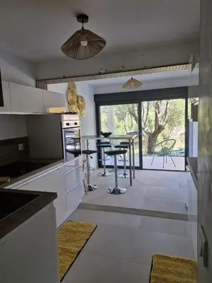 a dining room table with two chairs and a glass top at Maison Rez-de-jardin 80 m de la plage in Serra-di-Ferro