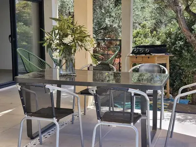 a dining room with a table and chairs and a patio at Maison Rez-de-jardin 80 m de la plage in Serra-di-Ferro
