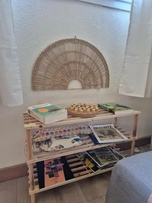 a table with a shelf with books and magazines at Appartement calme & cosy vue montagne in Corte