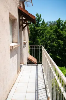 a balcony of a building with a fence and trees at Appartement calme & cosy vue montagne in Corte
