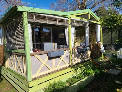 a yellow and green house with a porch at Chalet en bois climatisé À 300 m de la plage Marina di Sorbo 6 personnes in Sorbo-Ocagnano