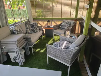 a screened in porch with chairs and a couch and a table at Chalet en bois climatisé À 300 m de la plage Marina di Sorbo 6 personnes in Sorbo-Ocagnano