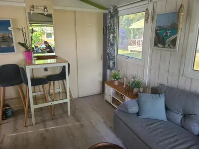 a living room with a couch and a desk in a tiny house at Chalet en bois climatisé À 300 m de la plage Marina di Sorbo 6 personnes in Sorbo-Ocagnano