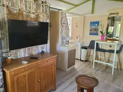 a living room with a flat screen tv on a wall at Chalet en bois climatisé À 300 m de la plage Marina di Sorbo 6 personnes in Sorbo-Ocagnano