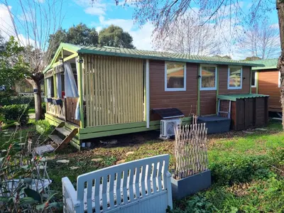 a tiny house with a green roof and a fence at Chalet en bois climatisé À 300 m de la plage Marina di Sorbo 6 personnes in Sorbo-Ocagnano