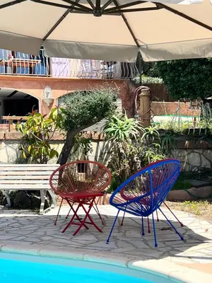 two chairs and an umbrella next to a pool at villa vue mer avec piscine et jardin arboré in Coggia