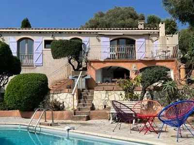 a house with two chairs next to a swimming pool at villa vue mer avec piscine et jardin arboré in Coggia