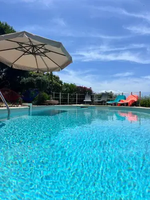 a large blue swimming pool with an umbrella at villa vue mer avec piscine et jardin arboré in Coggia