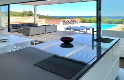 a kitchen and living room with a view of a pool at Villa Isulana, piscine chauffée, vue mer, proche Pinarello in Zonza