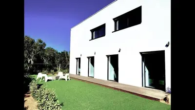 a white house with two white chairs on a lawn at Villa Isulana, piscine chauffée, vue mer, proche Pinarello in Zonza