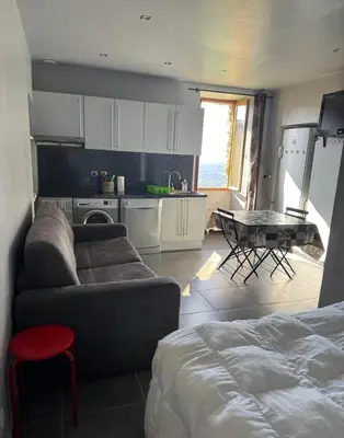 a living room with a couch and a table and a kitchen at Studio in Sartène