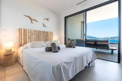 a bedroom with a white bed with birds flying above it at A Sereina - appt climatisé proche de la plage in Grosseto-Prugna