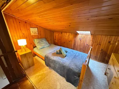 a small bedroom with a bed in a wooden room at L'Alcôve - Wifi, TV, Central in Bonifacio
